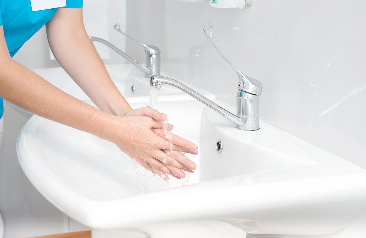 Kuvassa hoitaja pesee käsiään
